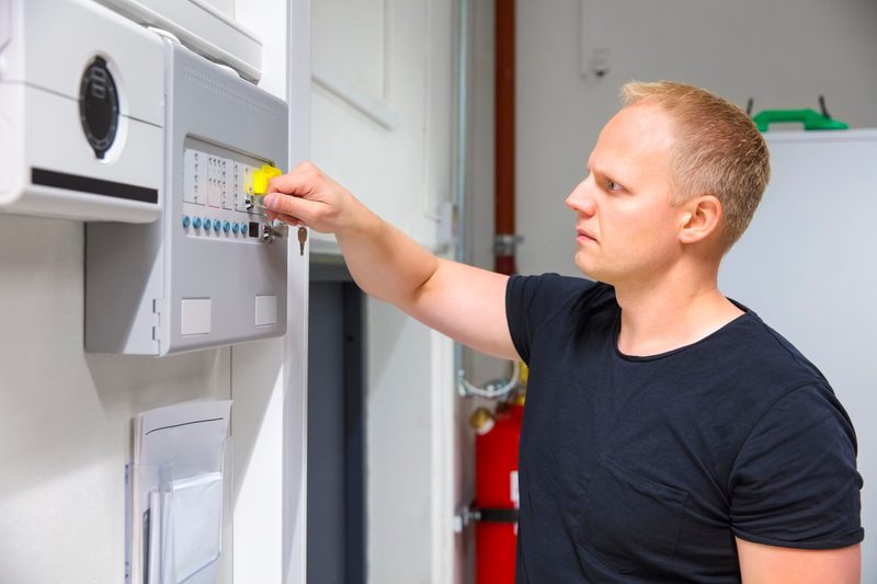 Technician servicing commercial fire alarm panel in Tucson